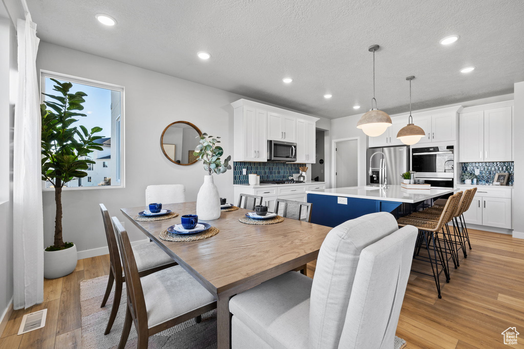 Dining space featuring a textured ceiling and light hardwood / wood-style flooring