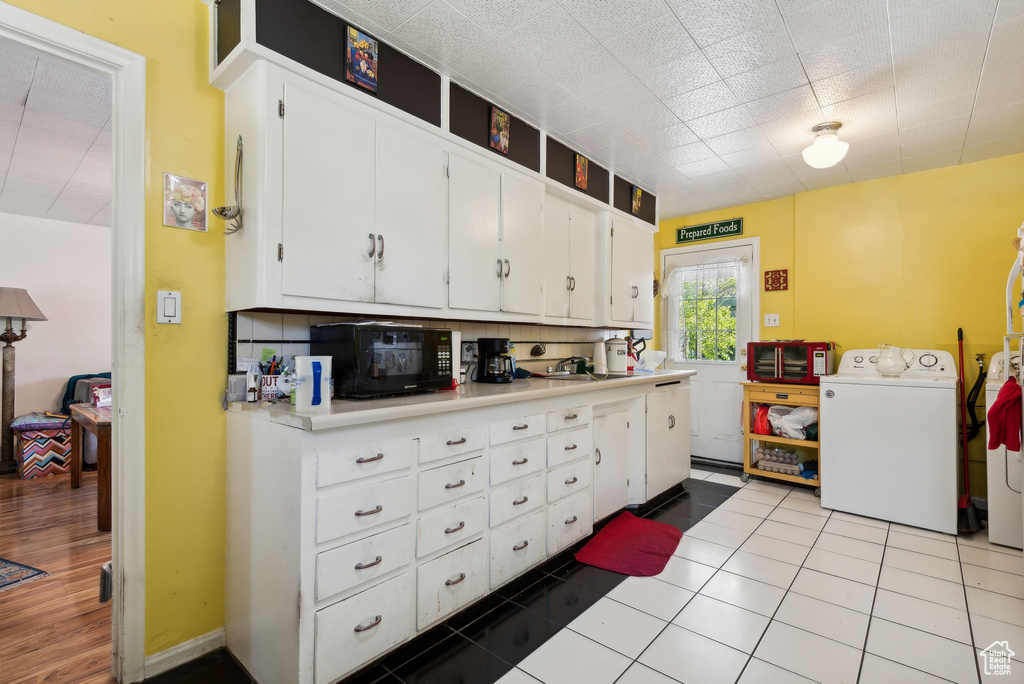 Kitchen with decorative backsplash, white cabinetry, sink, and light tile patterned floors