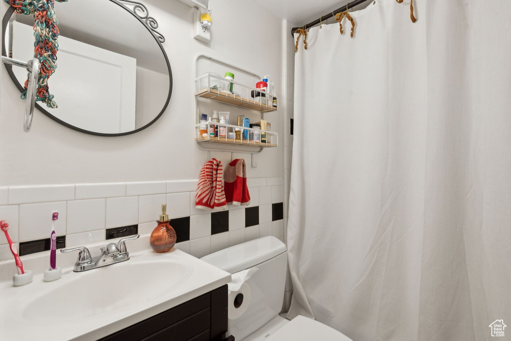 Bathroom with vanity, tile walls, toilet, and tasteful backsplash