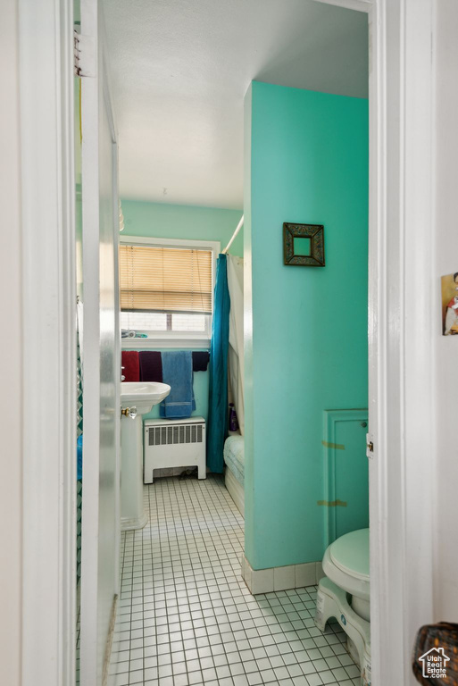 Bathroom with tile patterned flooring, toilet, and radiator heating unit