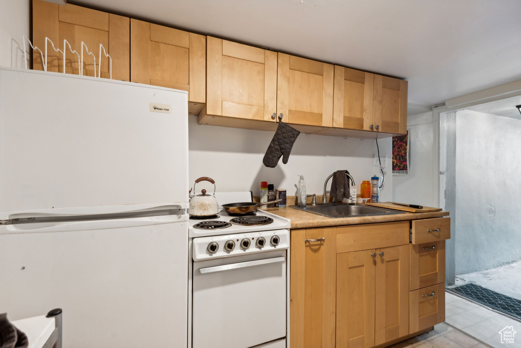 Kitchen with light brown cabinets, sink, and white appliances