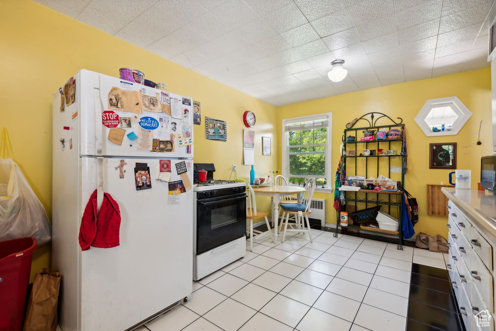 Kitchen featuring white cabinets, white appliances, and light tile patterned floors