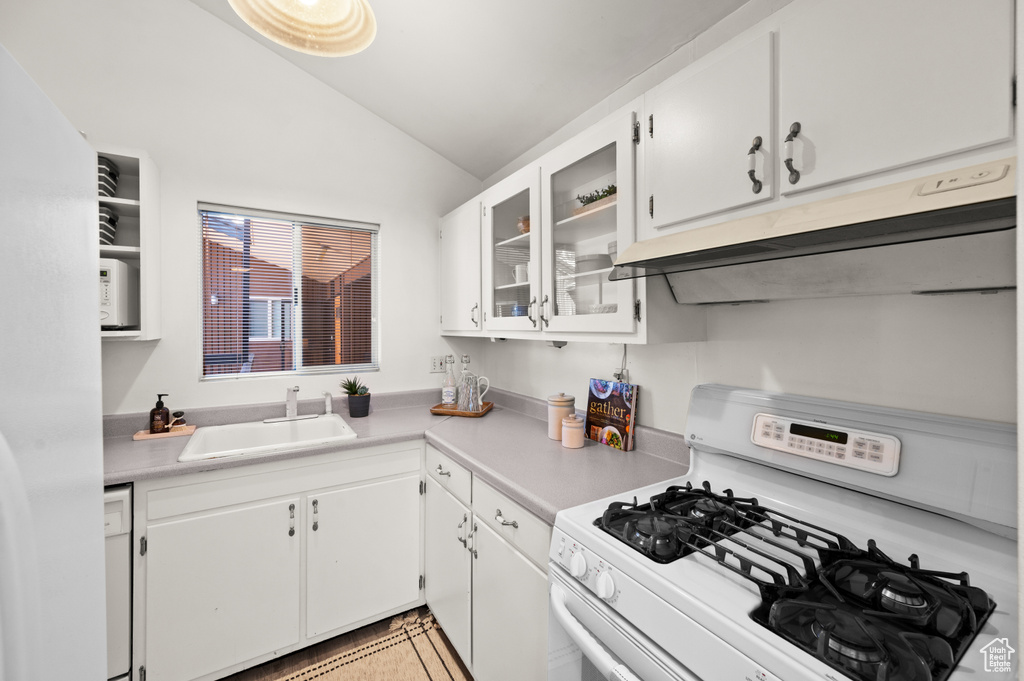 Kitchen featuring white cabinetry, white appliances, light tile patterned floors, lofted ceiling, and sink