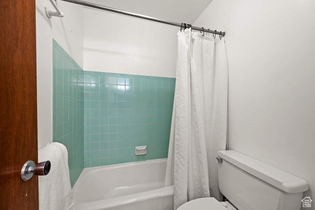 Bathroom featuring shower / bath combination with curtain and toilet