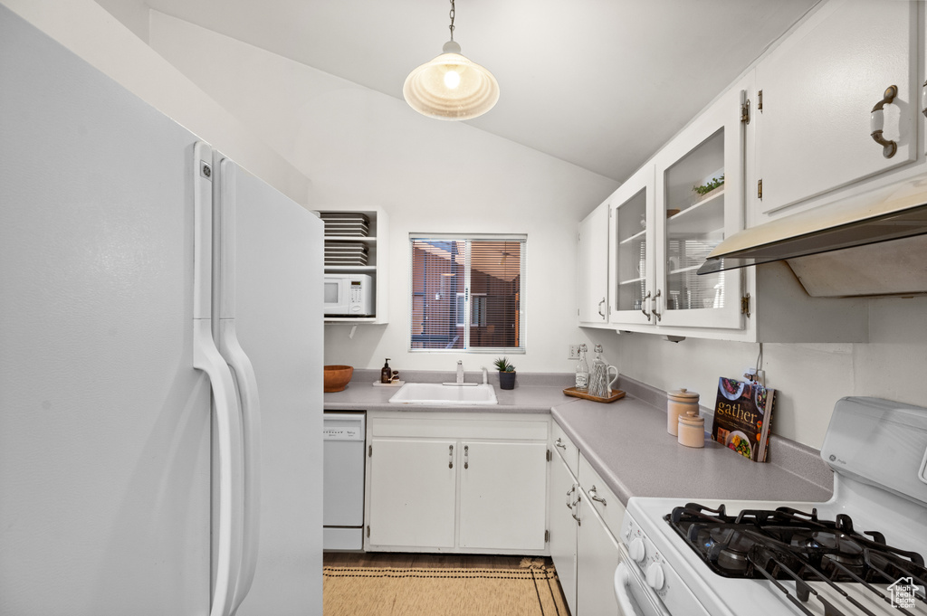 Kitchen with sink, lofted ceiling, white cabinetry, hanging light fixtures, and white appliances