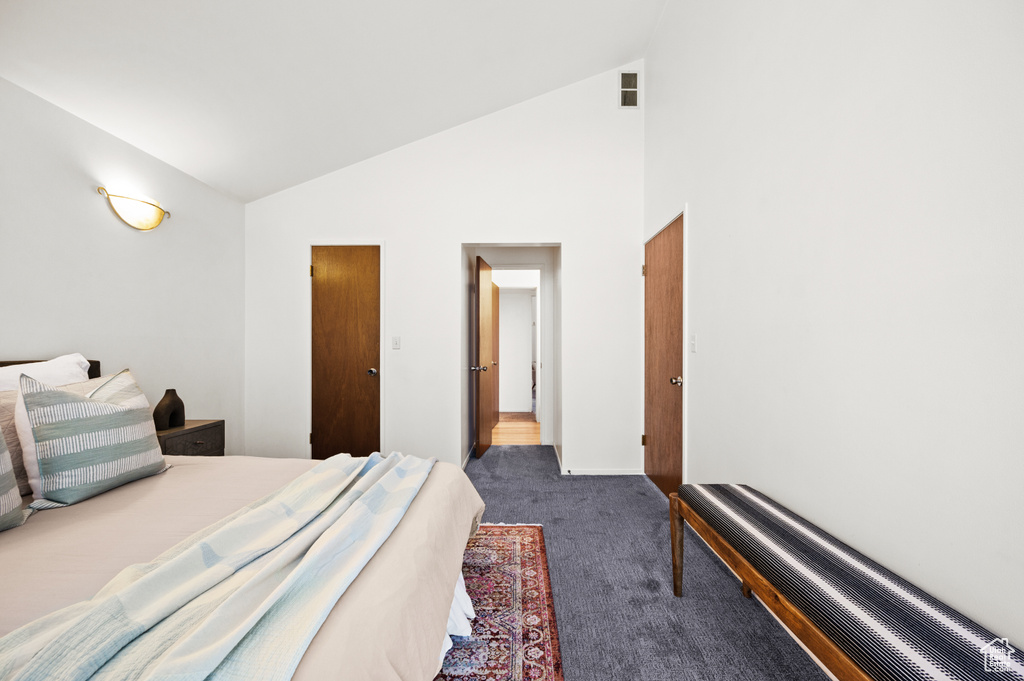 Bedroom featuring high vaulted ceiling and dark colored carpet