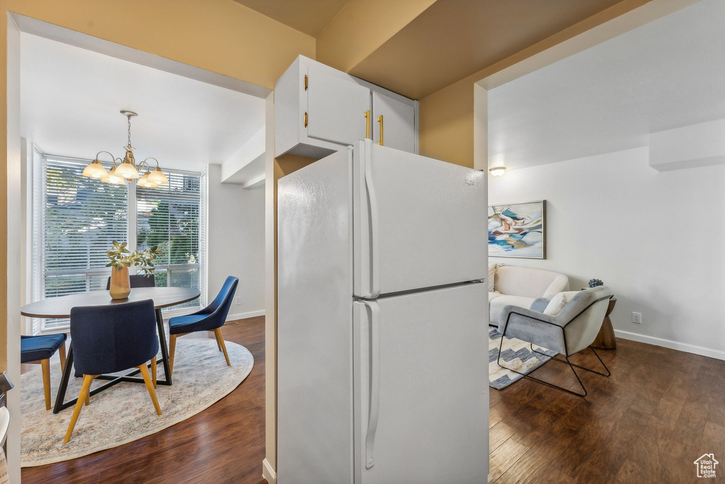 Kitchen featuring white cabinetry, dark hardwood / wood-style flooring, white fridge, decorative light fixtures, and a notable chandelier