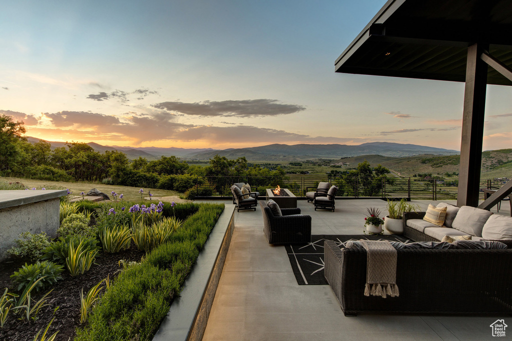 Patio terrace at dusk featuring an outdoor hangout area, a mountain view, and a patio area