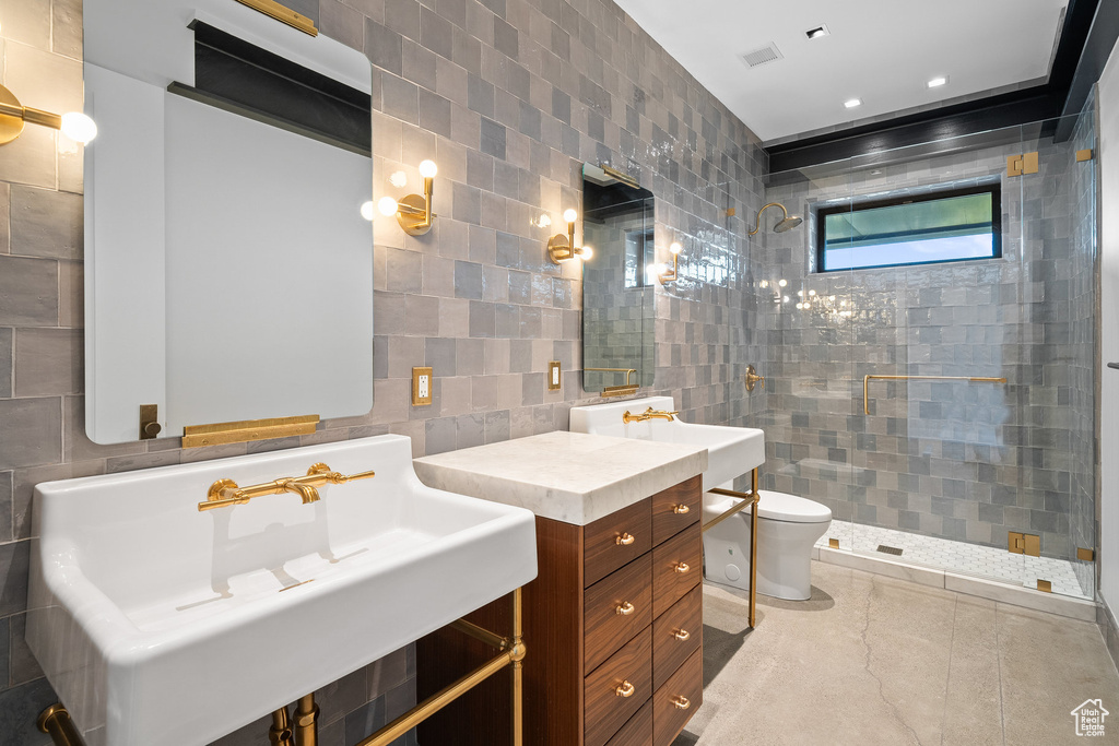 Full bath with tile walls, a tile shower, and vanity