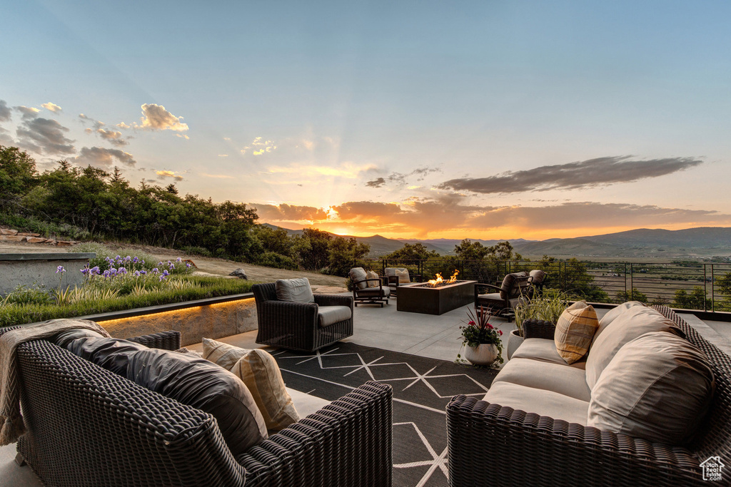 Patio terrace at dusk featuring an outdoor living space with a fire pit, a patio area, and a mountain view