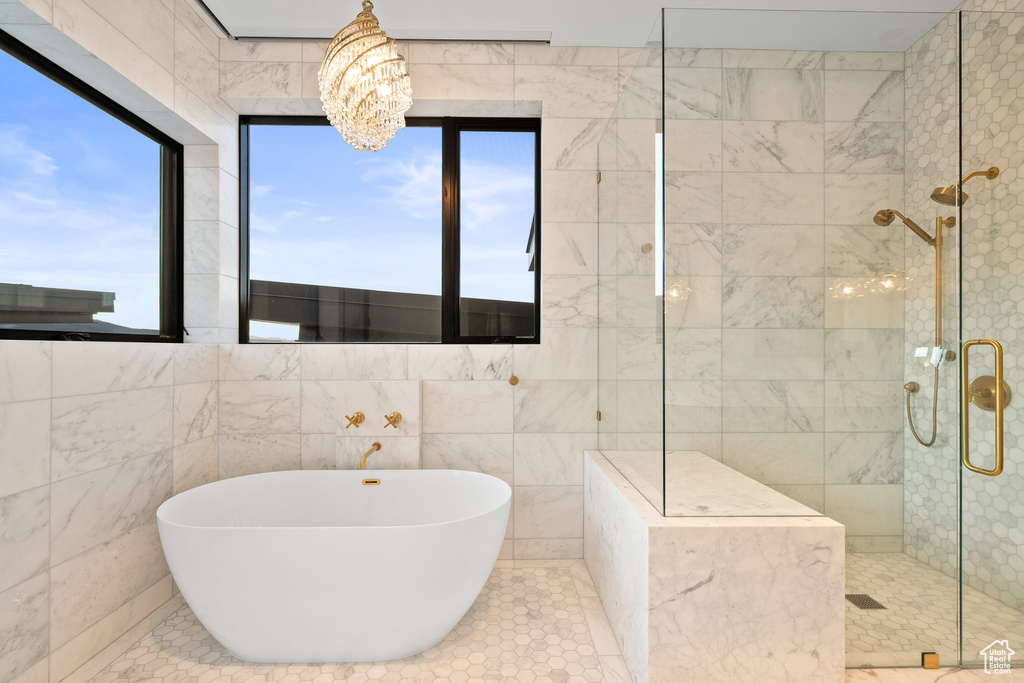 Full bathroom with a soaking tub, a tile shower, a chandelier, and tile walls
