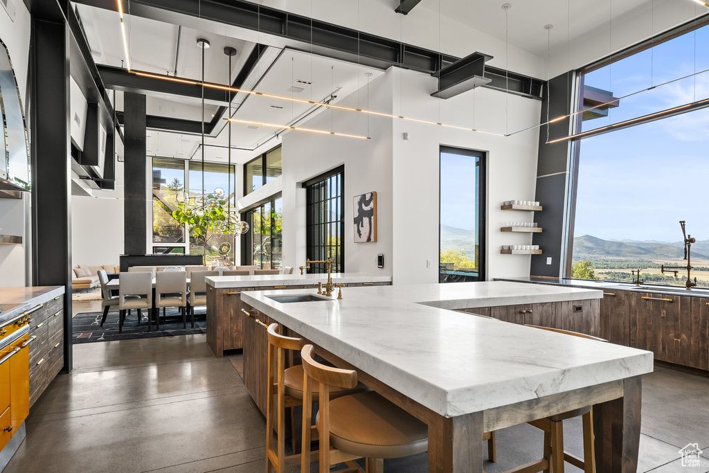 Kitchen with modern cabinets, a large island, finished concrete flooring, a mountain view, and a towering ceiling
