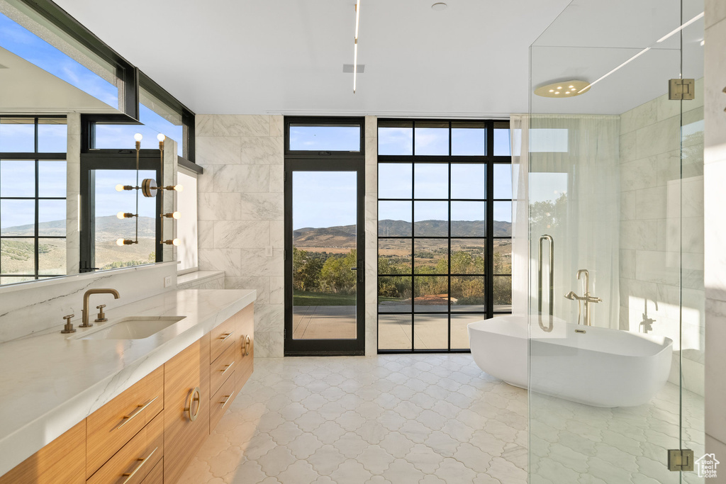 Bathroom featuring floor to ceiling windows, vanity, a freestanding tub, a mountain view, and a stall shower