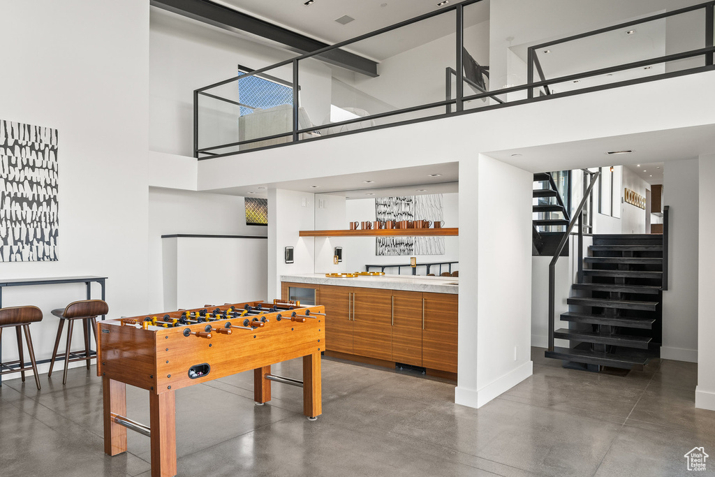 Recreation room featuring concrete flooring, a high ceiling, and bar with sink