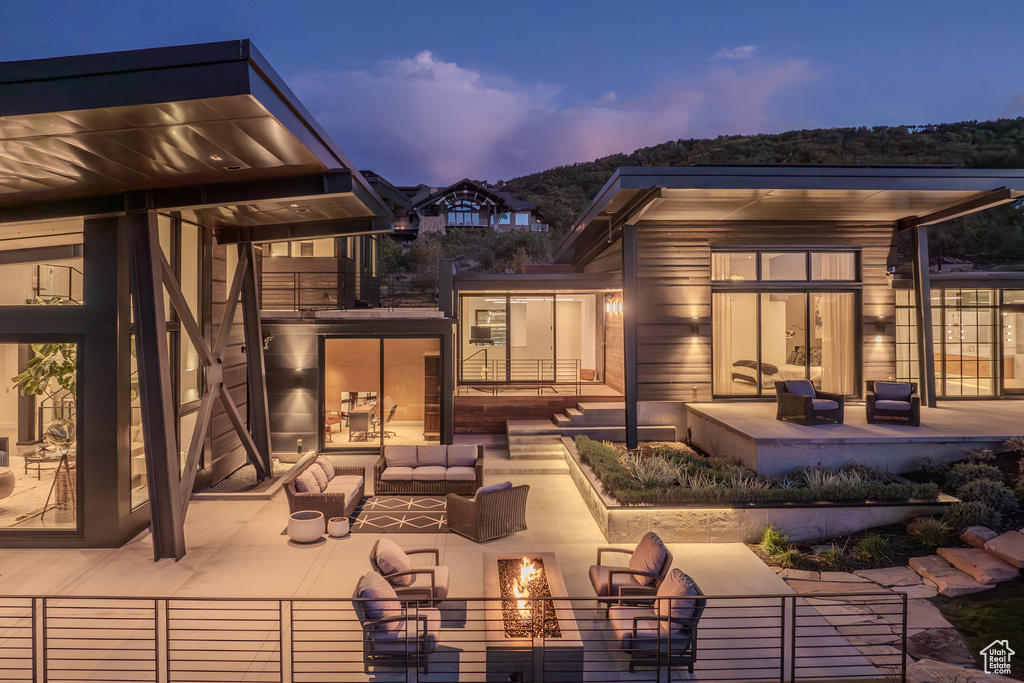 Back of house at dusk with an outdoor living space with a fire pit and a patio area