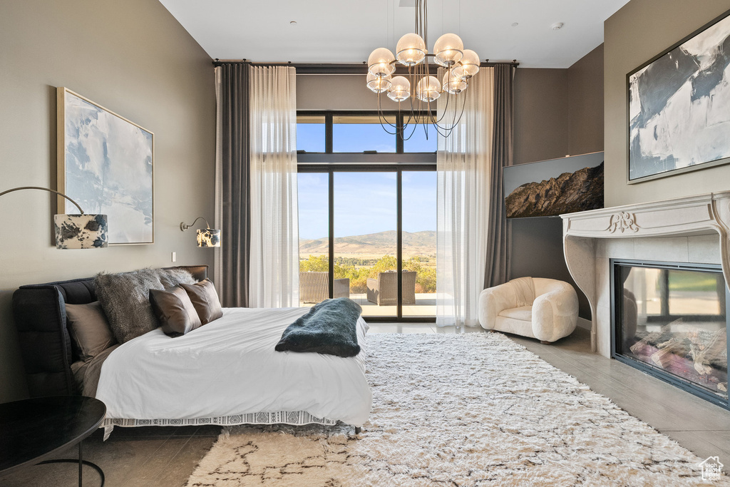 Bedroom with a chandelier, multiple windows, a glass covered fireplace, and access to exterior