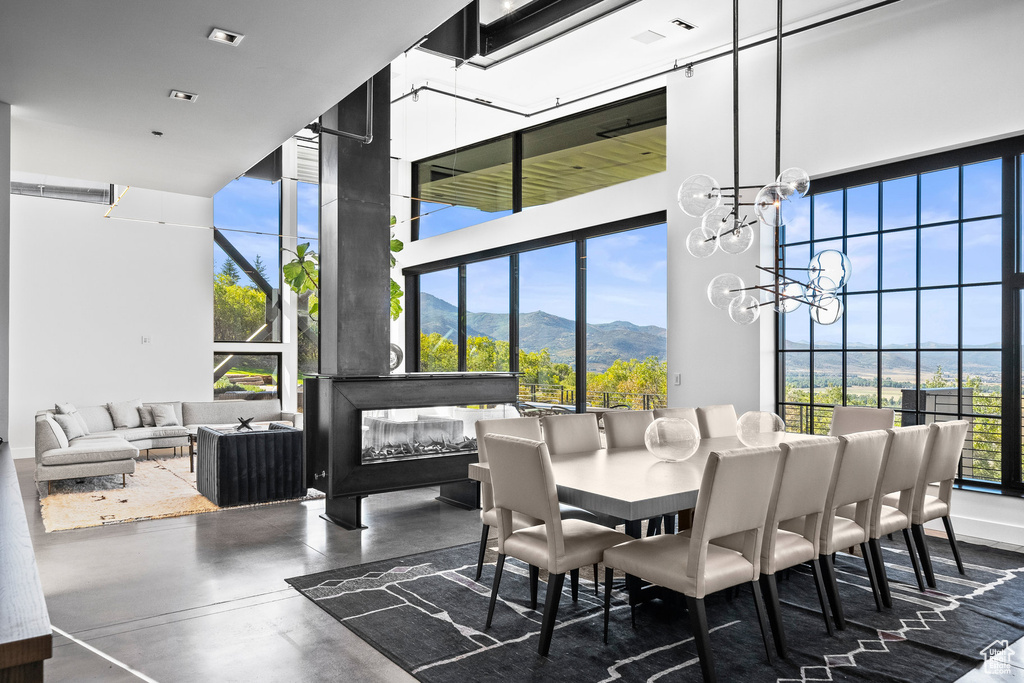 Dining area featuring a mountain view, a high ceiling, plenty of natural light, finished concrete floors, and a chandelier