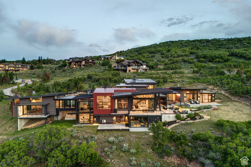 Rear view of house with a patio, a deck, and a forest view