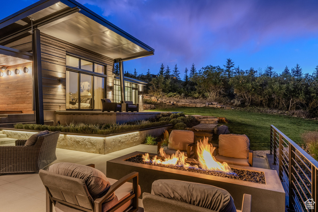 Patio terrace at dusk featuring an outdoor fire pit, a patio area, and a yard