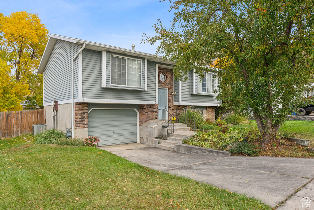 Split foyer home with central AC, a garage, and a front lawn