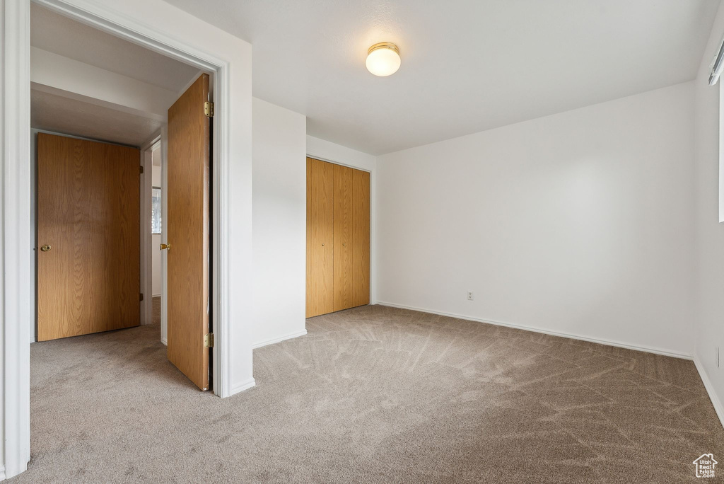 Unfurnished bedroom with a closet and light carpet