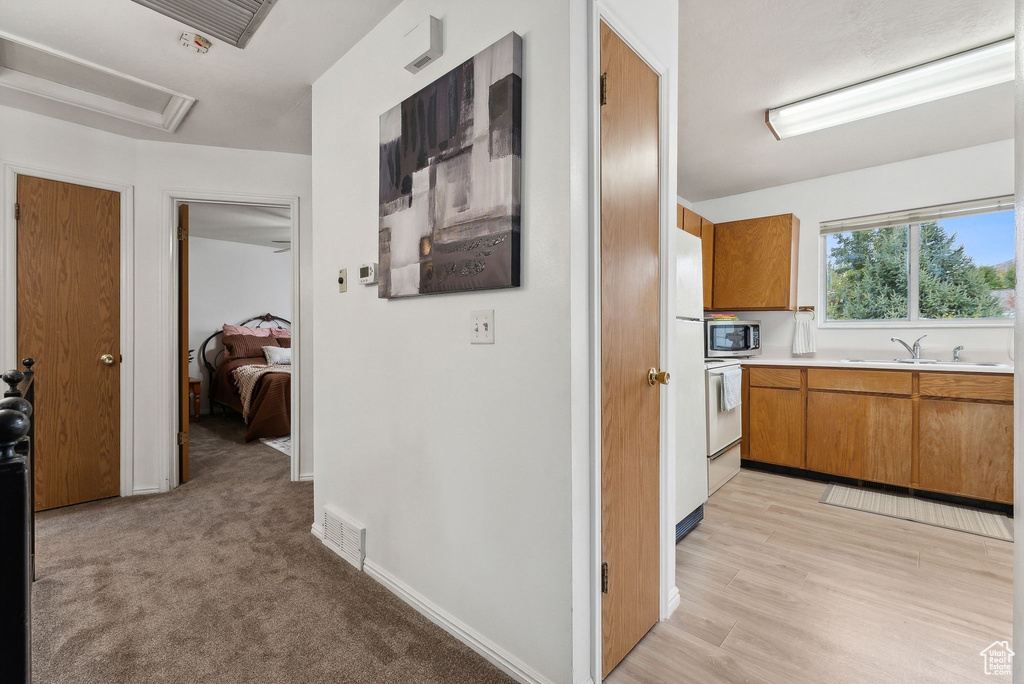 Corridor featuring light hardwood / wood-style flooring and sink