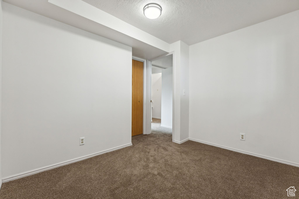 Carpeted empty room featuring a textured ceiling