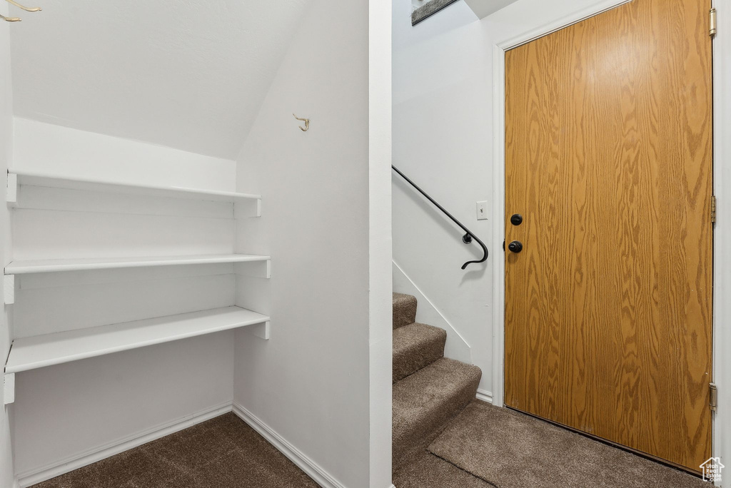 Stairway featuring carpet floors and vaulted ceiling