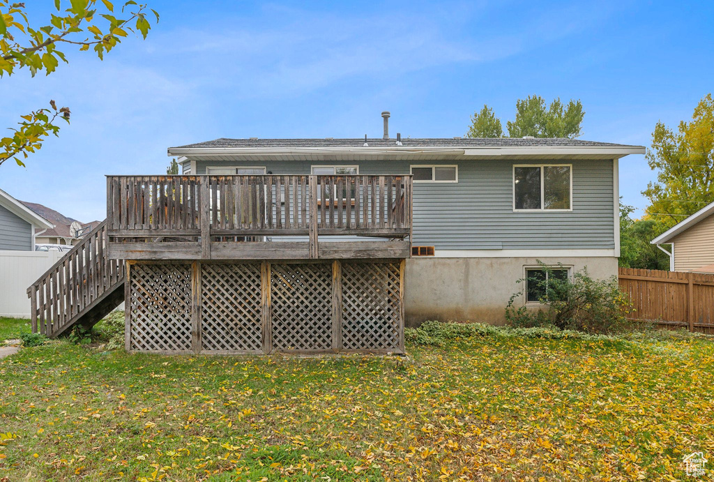 Rear view of property featuring a wooden deck and a yard