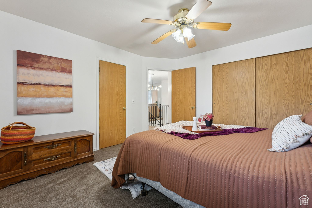 Carpeted bedroom with ceiling fan with notable chandelier