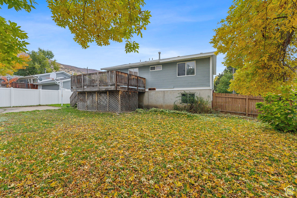 Rear view of house with a wooden deck and a lawn