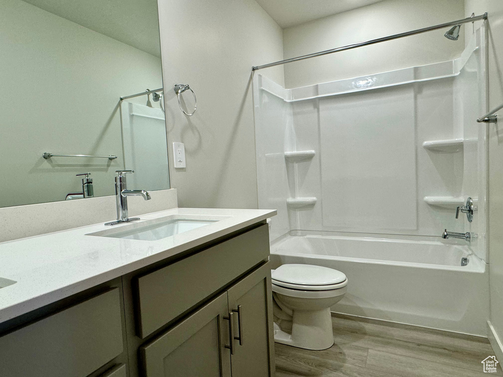 Full bathroom with hardwood / wood-style floors, vanity, toilet, and shower / bathing tub combination