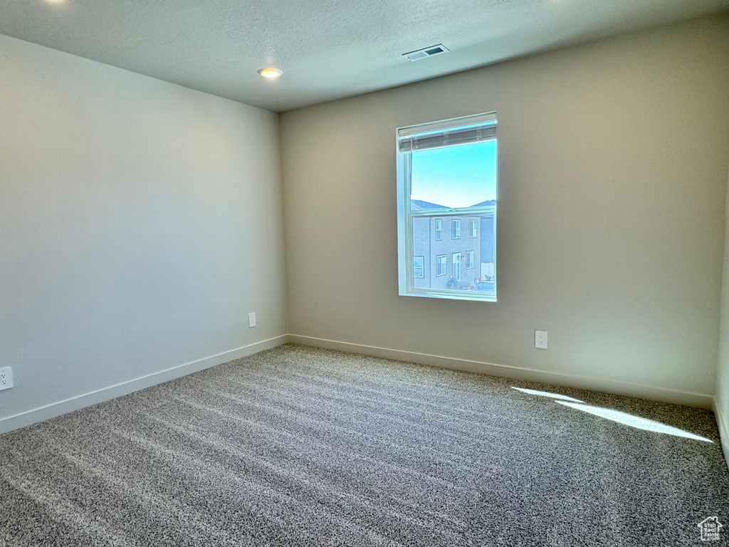 Empty room featuring carpet floors and a textured ceiling