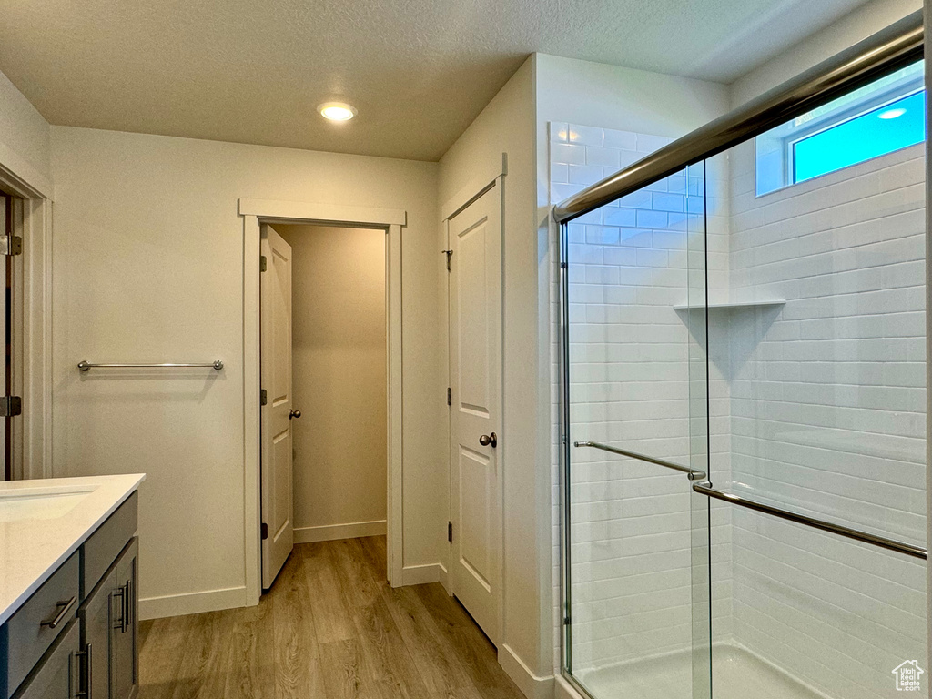 Bathroom featuring a textured ceiling, walk in shower, hardwood / wood-style flooring, and vanity