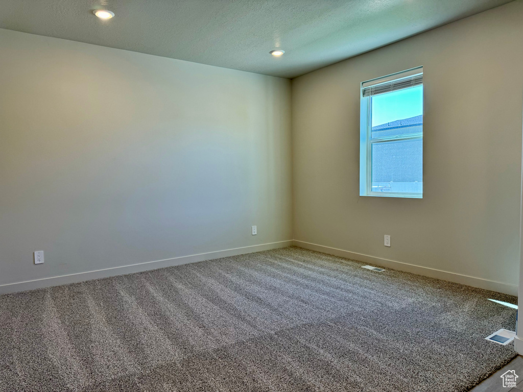 Carpeted spare room featuring a textured ceiling