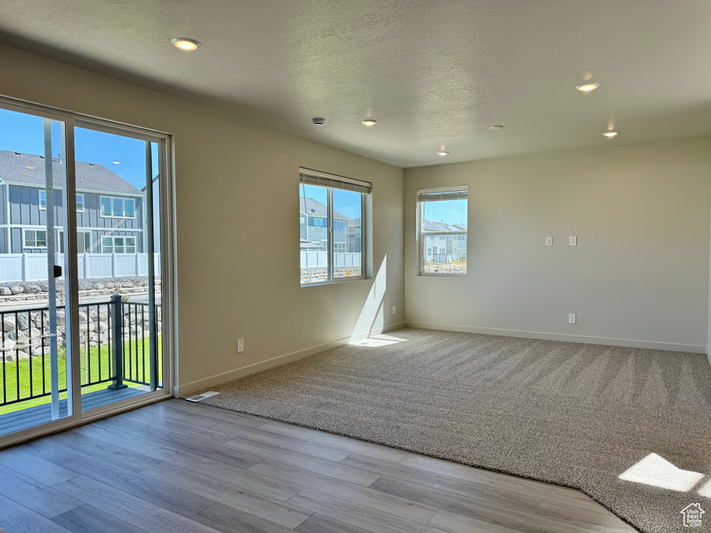 Unfurnished room featuring light wood-type flooring, a textured ceiling, and plenty of natural light