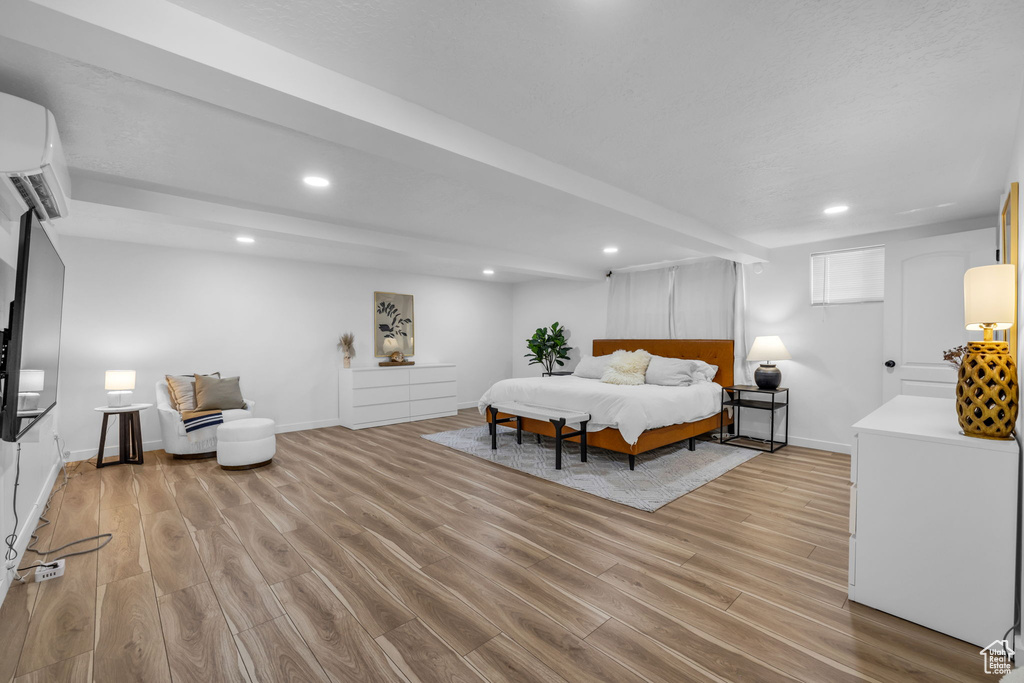 Bedroom with light hardwood / wood-style floors and a wall mounted air conditioner