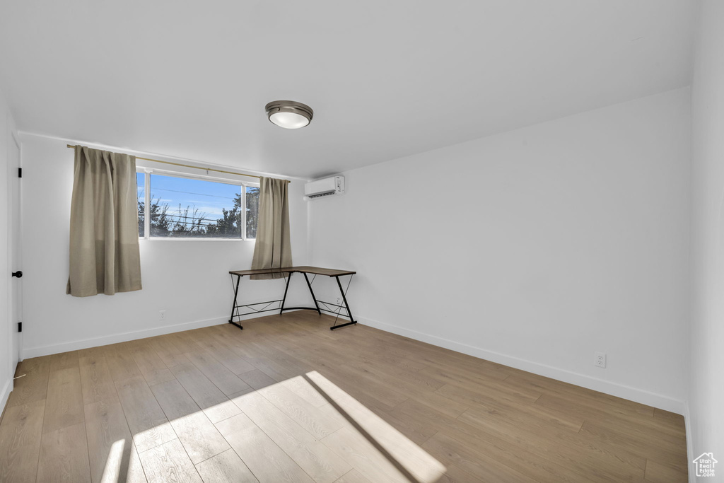 Spare room featuring light wood-type flooring and an AC wall unit