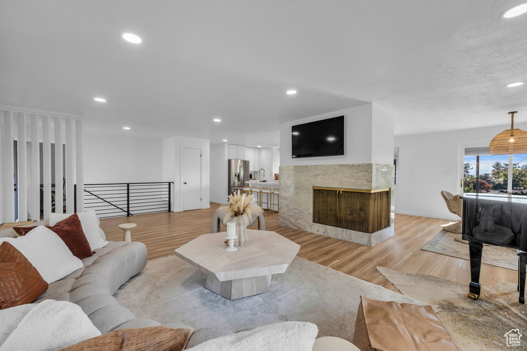 Living room featuring light wood-type flooring and a high end fireplace