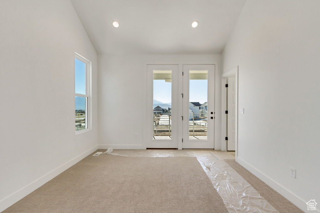 Carpeted empty room with a healthy amount of sunlight and vaulted ceiling