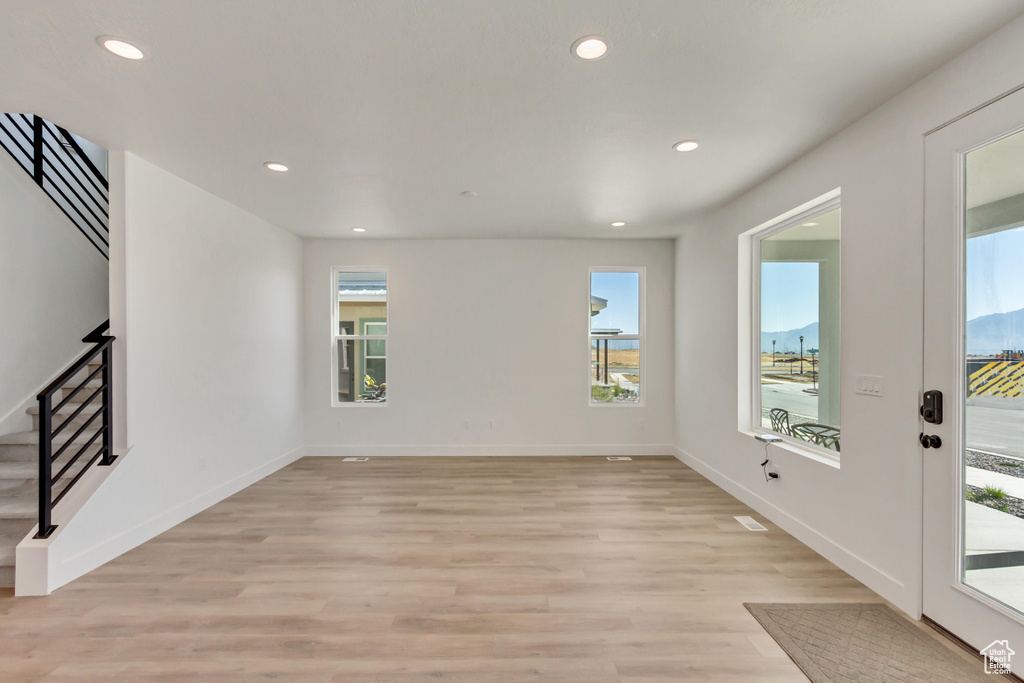 Unfurnished living room with a mountain view, light wood-type flooring, and a healthy amount of sunlight