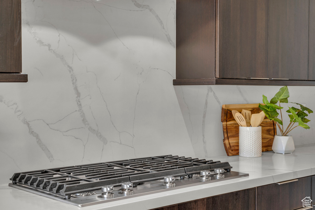 Room details featuring dark brown cabinetry, stainless steel gas cooktop, and decorative backsplash