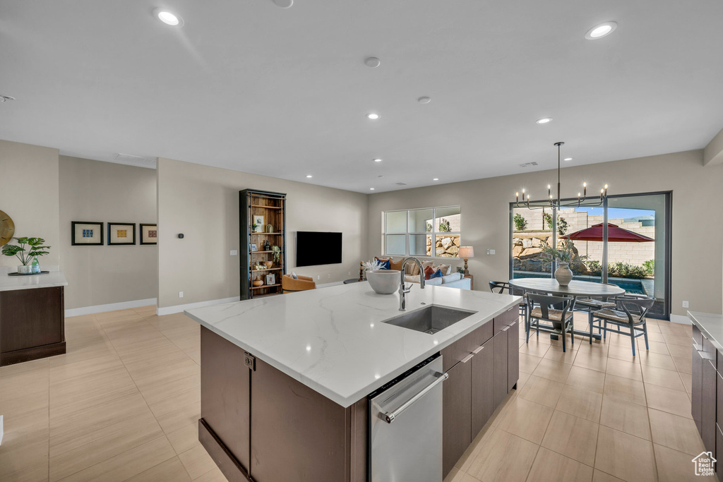 Kitchen with sink, a large island, decorative light fixtures, dishwasher, and an inviting chandelier