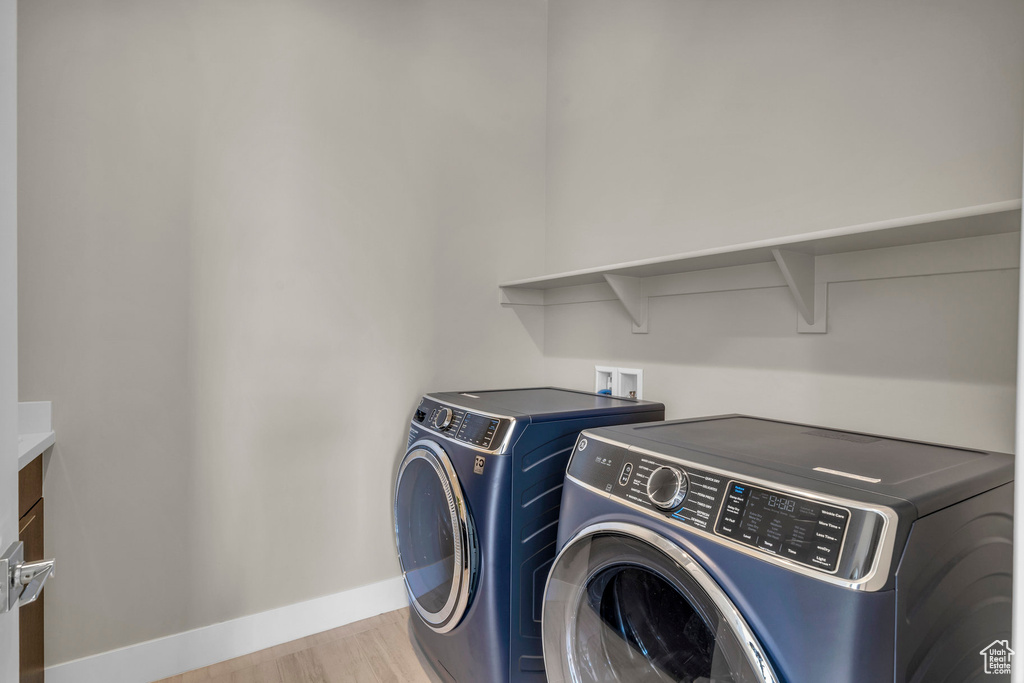 Washroom featuring washing machine and dryer and light hardwood / wood-style flooring