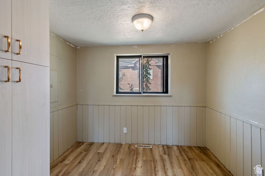 Unfurnished room with light hardwood / wood-style floors and a textured ceiling