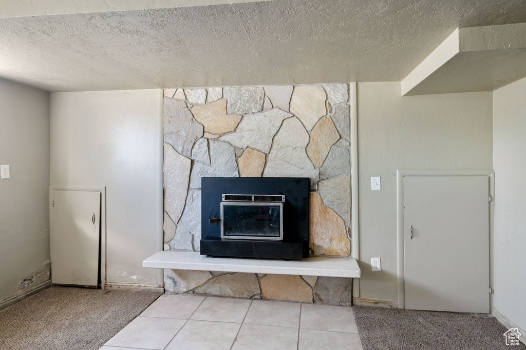 Interior details featuring a fireplace, a textured ceiling, and tile patterned flooring