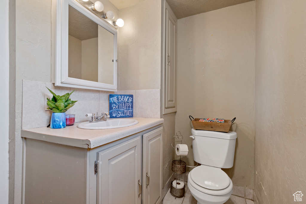 Bathroom with toilet, tile patterned floors, vanity, a textured ceiling, and backsplash