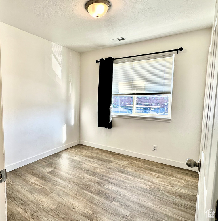 Spare room with a textured ceiling and hardwood / wood-style floors