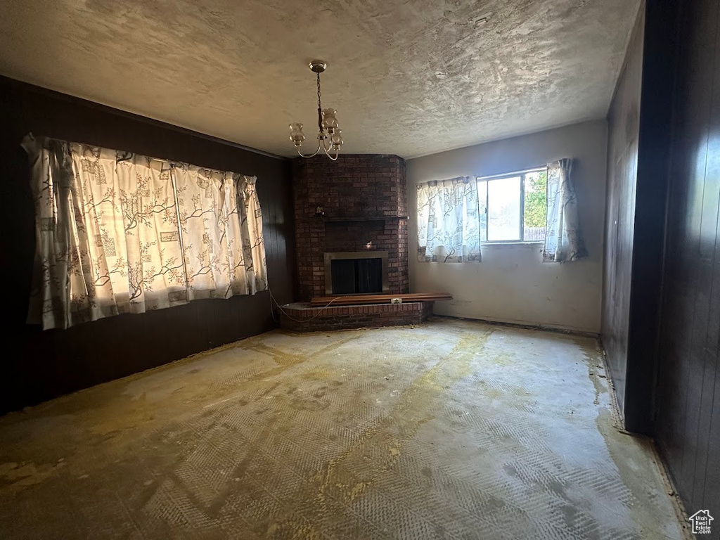 Unfurnished living room with an inviting chandelier and a brick fireplace