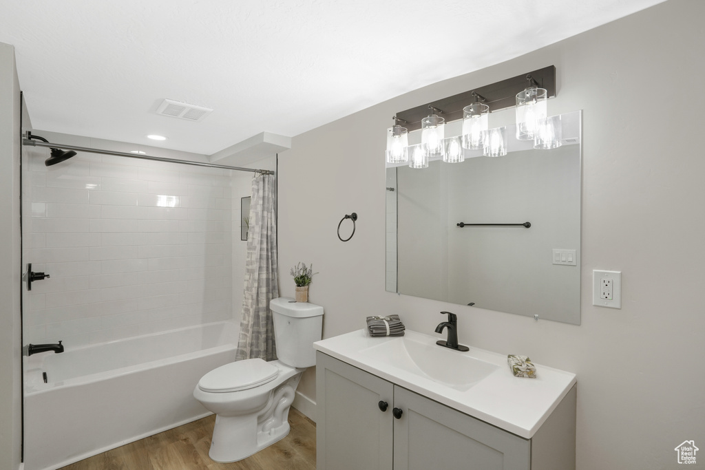 Full bathroom featuring wood-type flooring, vanity, toilet, and shower / tub combo